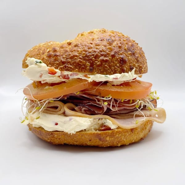 A bagel sandwich from The Dough Miner, filled with cream cheese, tomatoes, sprouts, and deli meat.