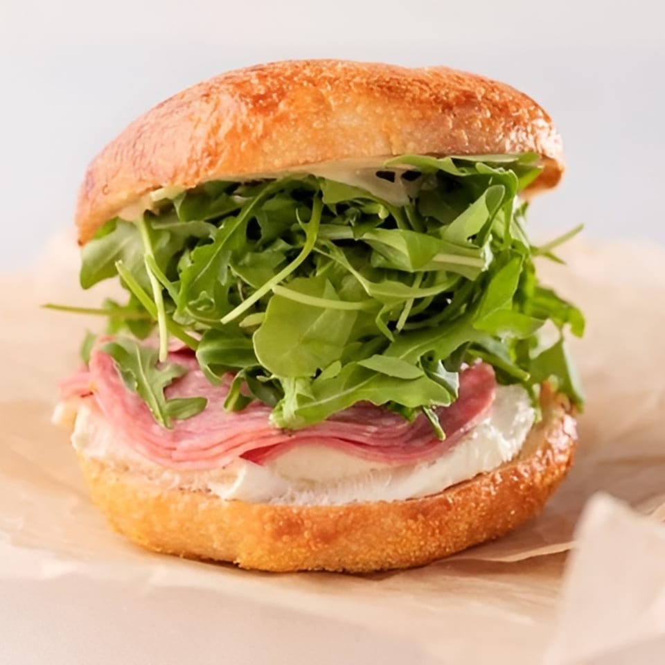 A Dough Miner sandwich with salami, cheese, and arugula on a toasted bun.